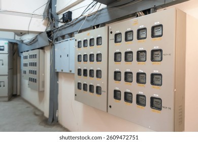 An image featuring an electrical distribution panel in an industrial setting. The panel displays multiple meters and circuit breakers, essential for monitoring and control.