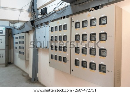 An image featuring an electrical distribution panel in an industrial setting. The panel displays multiple meters and circuit breakers, essential for monitoring and control.