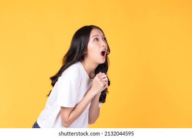Image of feeling excited, shock, surprise and happy. Young asian woman standing on yellow background. Female face expressions and emotions body language concept.