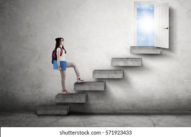 Image of a female college student walking on the stairs while carrying backpack toward an opportunity door to success