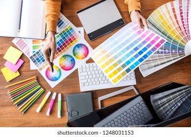 Image of female creative graphic designer working on color selection and drawing on graphics tablet at workplace with work tools and accessories, top view workspace. - Powered by Shutterstock