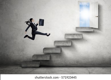 Image of a female entrepreneur jumping on the stairs while carrying a briefcase toward an opportunity door to success