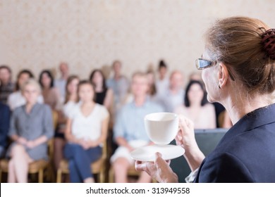 Image Of Female Lecturer Drinking Coffee During Discussion Panel