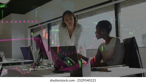 Image of financial data processing against two diverse women discussing over laptop at office. Global finance and business technology concept