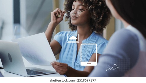 Image of financial data processing with icons over diverse colleagues discussing work in office. Global finances, business and digital interface concept digitally generated image.