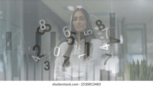Image of financial data processing with numbers over biracial businesswoman working at office. Global business, finances and digital interface concept digitally generated image.