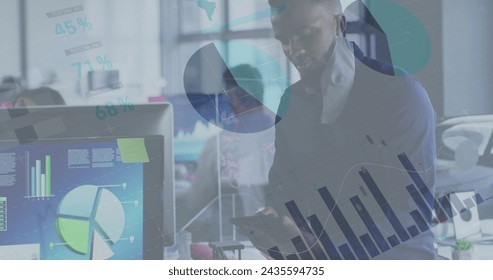 Image of financial data processing over businessman with face mask using tablet in office. global business and digital interface during covid 19 pandemic concept digitally generated image.