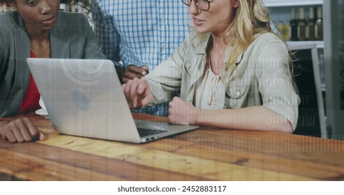 Image of financial data processing over diverse business people using laptop. Global business, finances, computing and data processing concept digitally generated image.