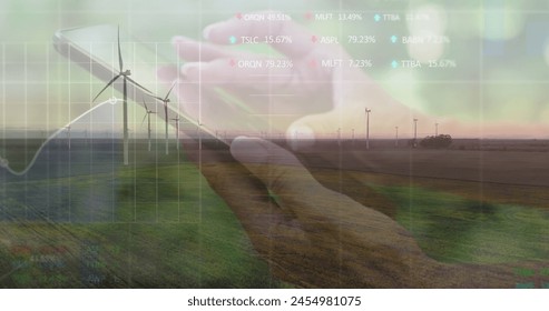 Image of financial data processing over caucasian woman using smartphone and wind turbine. global environment, sustainability and finance concept digitally generated image.