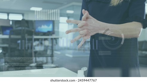 Image of financial data processing over caucasian businesswoman disinfecting hands in office. Global covid 19 pandemic, business, computing and data processing concept digitally generated image. - Powered by Shutterstock