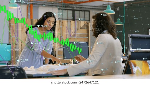 Image of financial data processing over diverse businesswomen working in office. Global business, finances, computing and data processing concept digitally generated image.