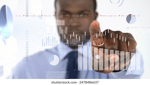 Image of financial data processing over african american businessman pointing finger. Global business, finances, computing and data processing concept digitally generated image.