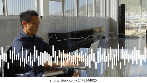 Image of financial data processing over asian businessman using laptop. Global computing, digital interface and data processing concept digitally generated image.
