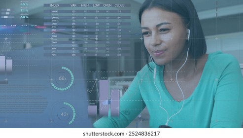 Image of financial data processing over biracial woman using laptop. Global finance, business, connections, computing and data processing concept digitally generated image.