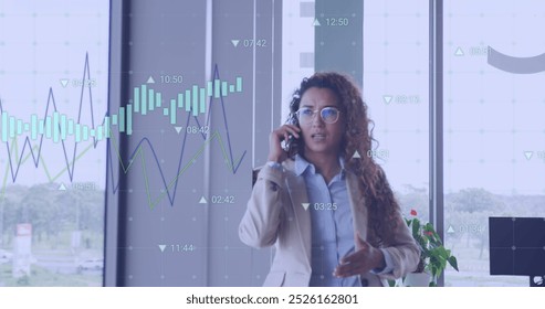 Image of financial data processing over biracial businesswoman talking on smartphone. Global business, computing and digital interface concept digitally generated image.