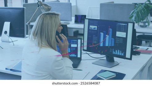 Image of financial data processing over caucasian woman talking on smartphone at office. Global finance and business technology concept
