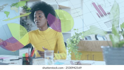 Image of financial data processing over african american businesswoman working in office. Global business, finance, computing and data processing concept digitally generated image.