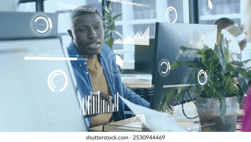Image of financial data processing over african american businessman working in office. Global business, finance, computing and data processing concept digitally generated image.
