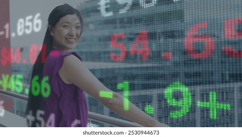 Image of financial data processing over asian businesswoman smiling on office balcony. Global business, finance, computing and data processing concept digitally generated image.