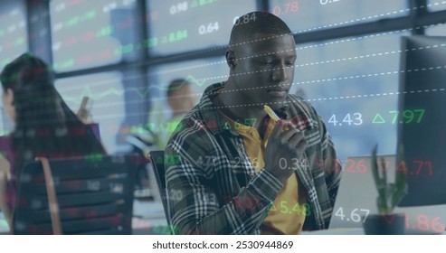 Image of financial data processing over african american businessman working in office. Global business, finance, computing and data processing concept digitally generated image.