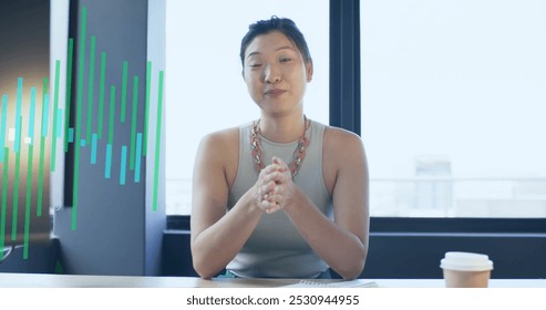 Image of financial data processing over asian businesswoman working in office. Global business, finance, computing and data processing concept digitally generated image.