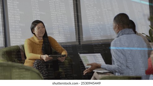 Image of financial data processing over diverse businesspeople working in office. Global business, finance, computing and data processing concept digitally generated image.