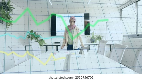 Image of financial data processing over biracial businesswoman in hijab working in office. Global business, finance, computing and data processing concept digitally generated image. - Powered by Shutterstock