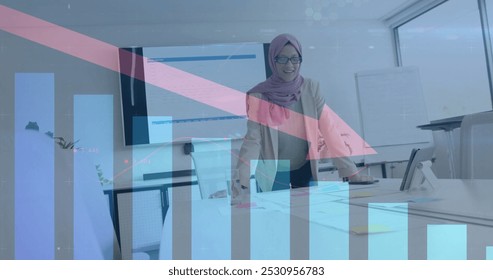 Image of financial data processing over biracial businesswoman in hijab working in office. Global business, finance, computing and data processing concept digitally generated image. - Powered by Shutterstock