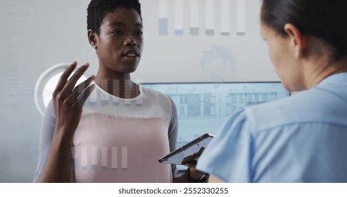 Image of financial data processing over diverse colleagues discussing work in office. Global business, finances, computing, communication and digital interface concept digitally generated image.