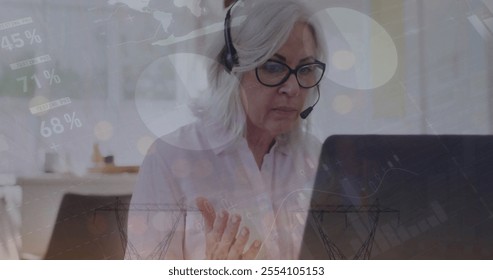 Image of financial data processing over senior caucasian woman using phone headset and laptop. Senior lifestyle, finances, communication and digital interface concept digitally generated image. - Powered by Shutterstock