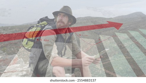 Image of financial data processing over caucasian man reading map in mountains. Global travel, finances, computing and digital interface concept digitally generated image.