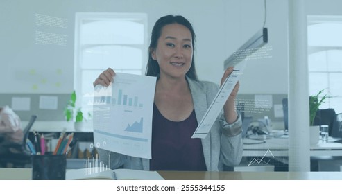 Image of financial data processing over asian businesswoman in office. Global finance, business, connections, computing and data processing concept digitally generated image. - Powered by Shutterstock