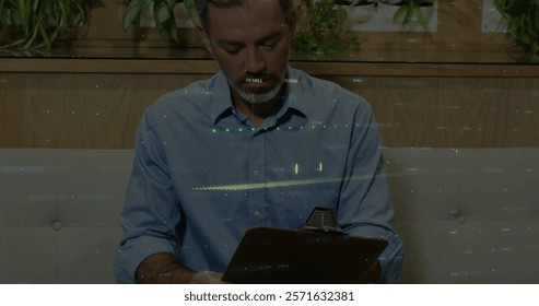 Image of financial data processing over caucasian male doctor taking notes. Global finances, medicine and digital interface concept digitally generated image.