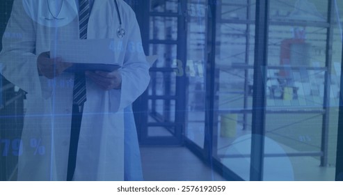 Image of financial data processing over caucasian male doctor in hospital. Global medicine, healthcare and digital interface concept digitally generated image.