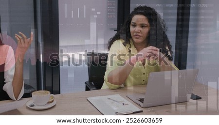 Image of financial data processing over diverse businesswomen in office. Global business, finance, computing and data processing concept digitally generated image.