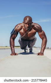 Image of fit young guy doing push-ups. Young fitness model exercising outdoors.
