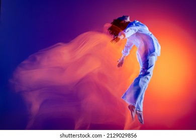 Image Of Flexible Young Girl, Hip-hop Dancer In White Outfit Dancing Hip Hop Isolated On Blue Background In Yellow Neon Light. Youth Culture, Hip-hop, Movement, Style And Fashion, Action.