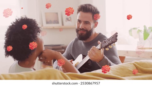 Image of flowers over happy diverse couple playing guitar together. Relationship, love, romance and lifestyle concept digitally generated image. - Powered by Shutterstock