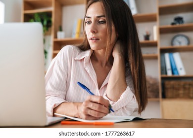 Image of focused adult businesswoman writing down notes while working with laptop in office - Shutterstock ID 1777263617