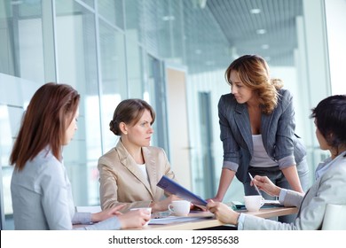 Image of four businesswomen discussing business plan at meeting