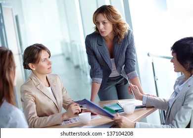 Image of four businesswomen discussing business plan at meeting