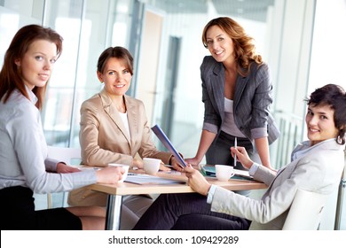 Image of four successful businesswomen looking at camera at meeting