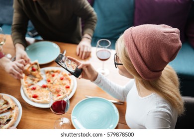 Image of friends sitting in cafe eating pizza while drinking alcohol and make a photo by phone. - Powered by Shutterstock