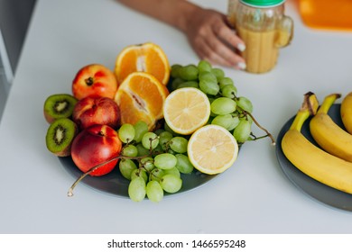 Image with fruit ingridients lying in the table. Female hand with glass of smoothie