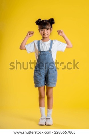 image full body of  asian little girl posing on a yellow background