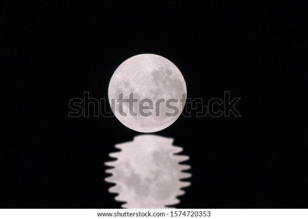 The image of the\
full moon with reflection