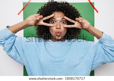 Image of funny african american woman making kiss lips and showing peace sign isolated over multicolored background