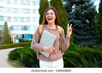Image of funny attractive girl pouting and showing v-sign.Happy student girl walks down the street in spring around the city