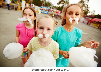 Image of funny girls with cotton candy posing on playground outdoors 