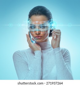 Image of Futuristic Attractive Businesswoman Wearing virtual Glasses Working With Holographic Hud Against Hightech background